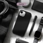 Flat lay of black iPhone 16e case with modern accessories including a smartwatch, folding knife, and AirTag on a concrete background.